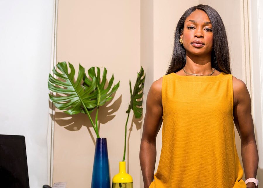 Stylish woman stands confidently in a modern office with plants and decor.